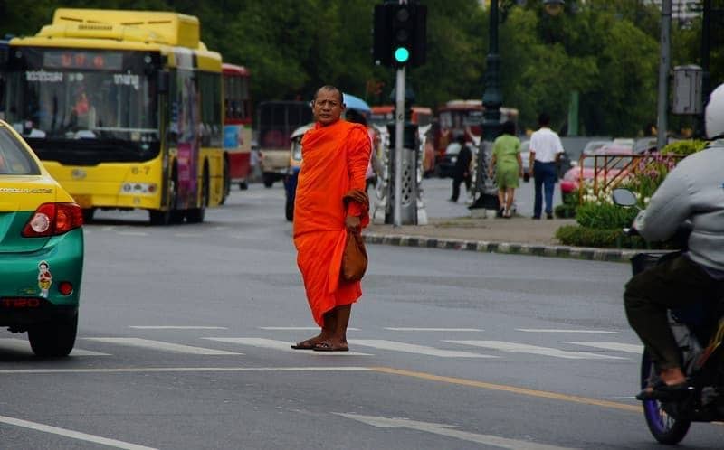 A Thai Monk stands in the middle of the cross walk waiting to get to the other side of the road - Bangkok, Thailand