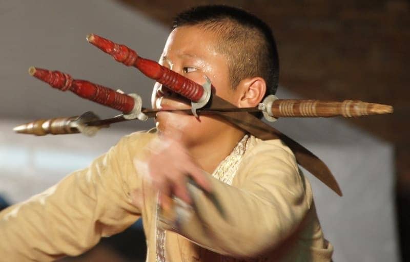 A Thai boy puts on a stunning display of theatrics by wielding a knife in his mouth during a performance in Chiang Mai, Thailand.