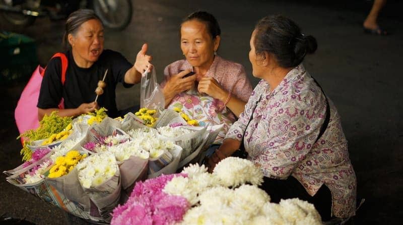 A group of Thai ladies engaging in conversation at a night bazaar in Chiang Mai, Thailand. 