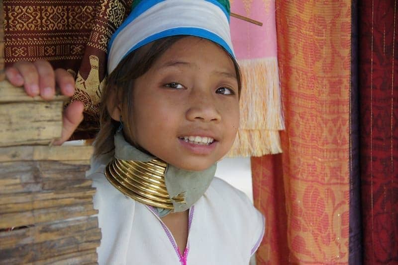 A cute girl from the Karen Hill tribe (long-neck) poses with a lovely smile in her village nearby Chiang Rai