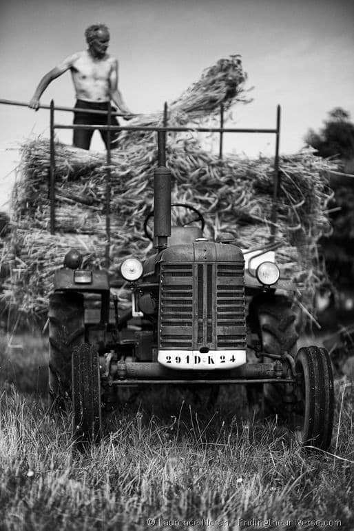 Red tractor and man with wheat on pitchfork