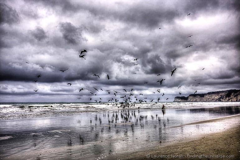 Frigate birds on beach Canoa people standing clouds