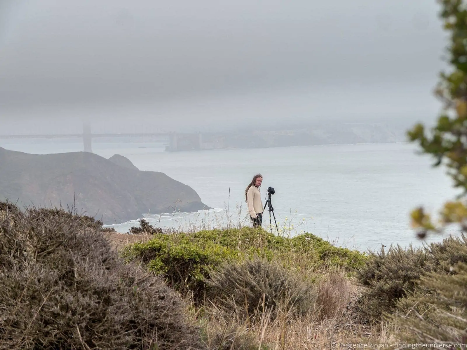 Behind-the-scenes shot of Laurence on the Marin Headlands road with cloud rolling in over the bay behind him