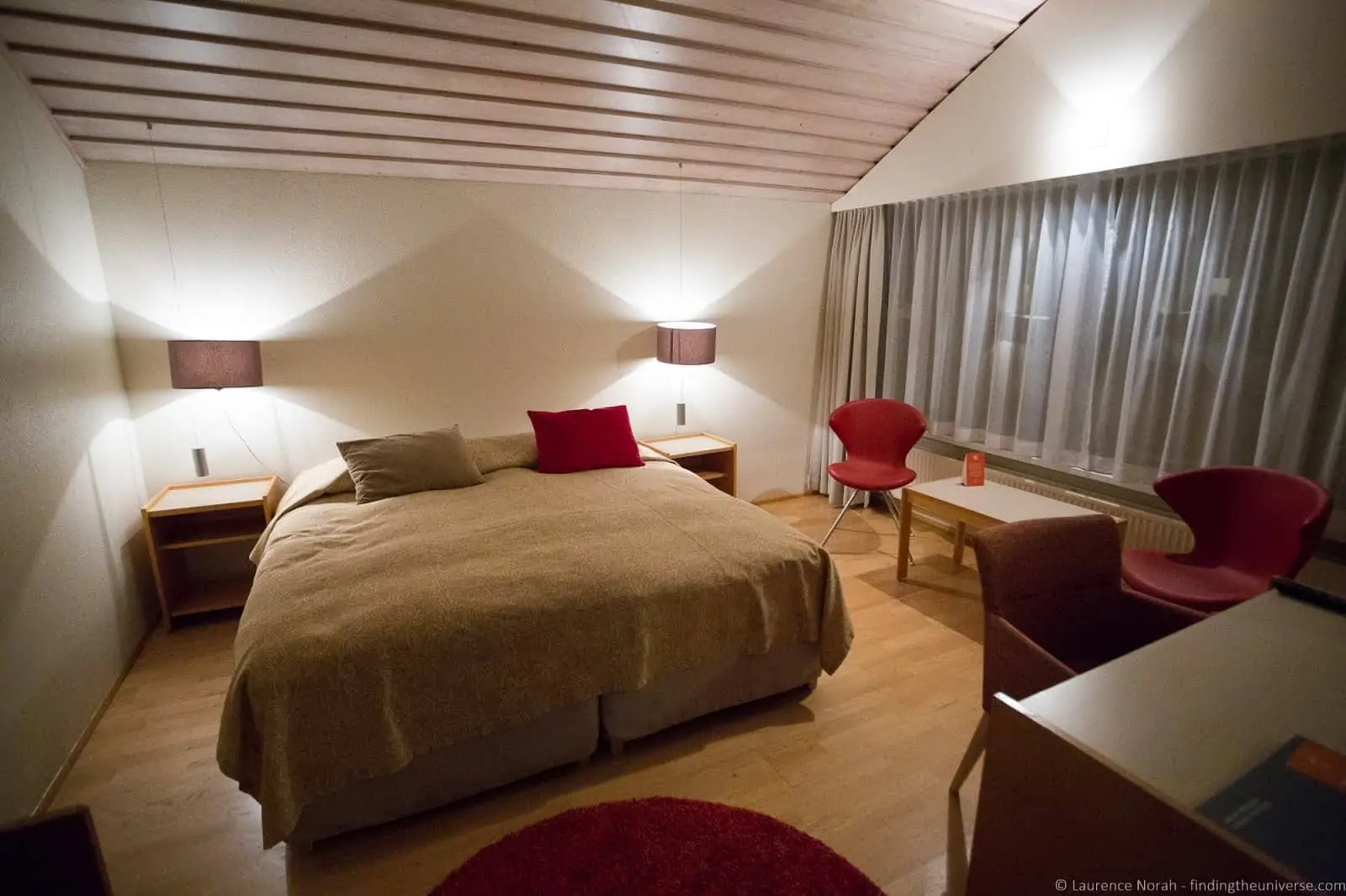 Compact Icelandic hotel room with wooden floor and bedside lamps at Flúðir