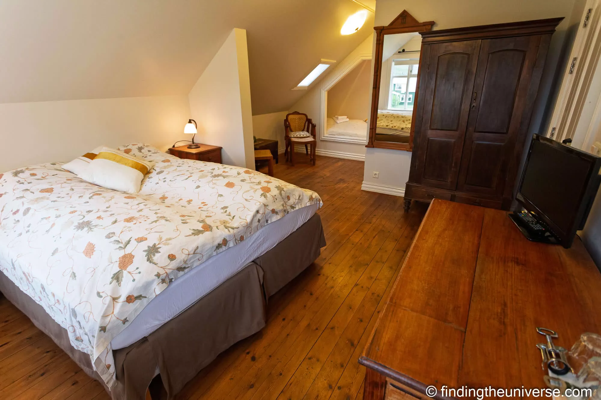 Aldan Hotel guest room with a patterned bedcover and dark wooden wardrobe