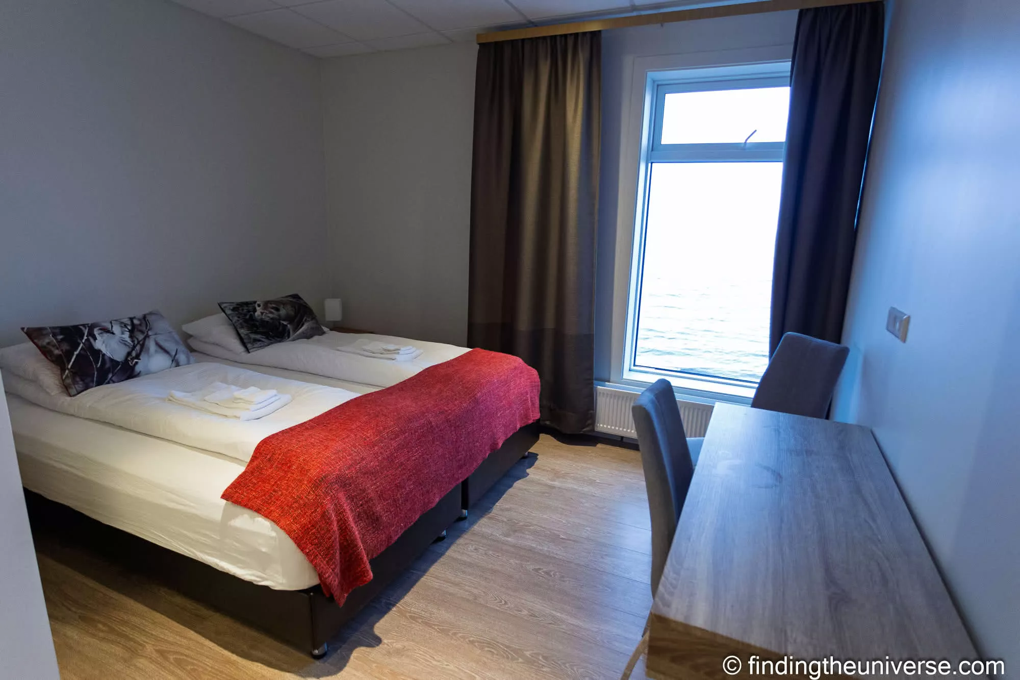 Guest room at Hotel West, with a red throw and a window onto the fjord