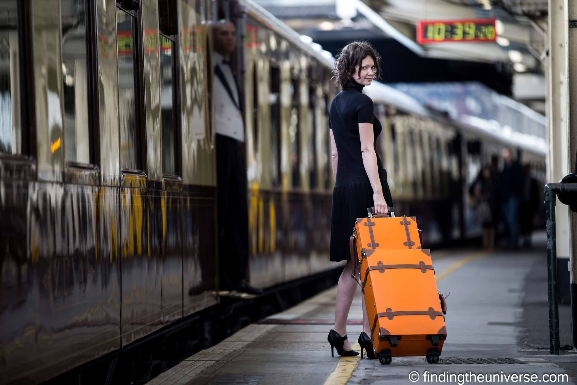 Girl with luggage on train platform by Laurence Norah
