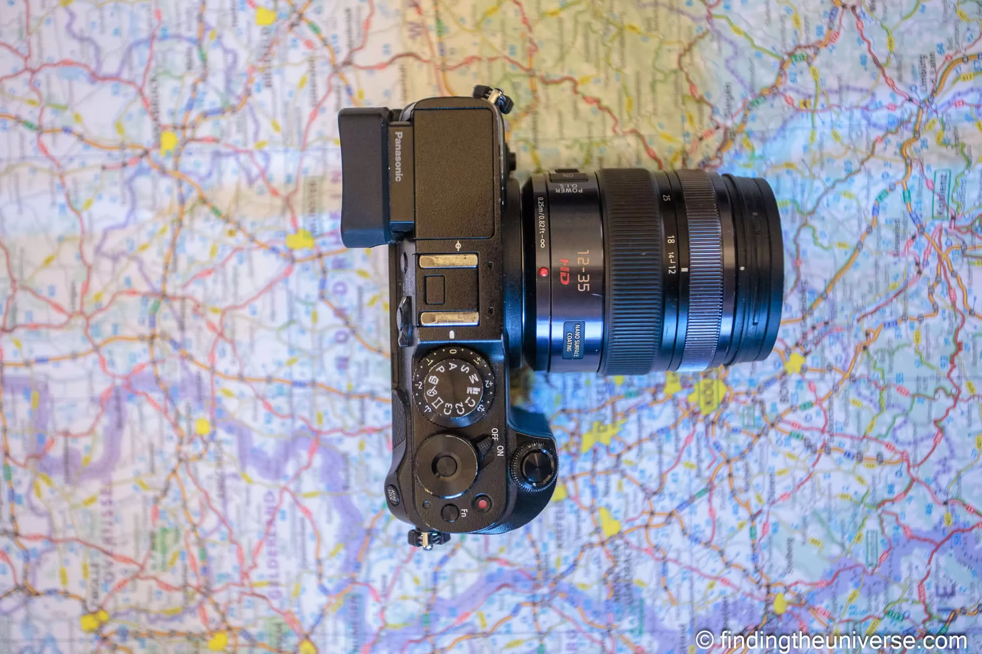 A Panasonic Lumix camera resting on a paper map, its mode dial turned to A for aperture priority