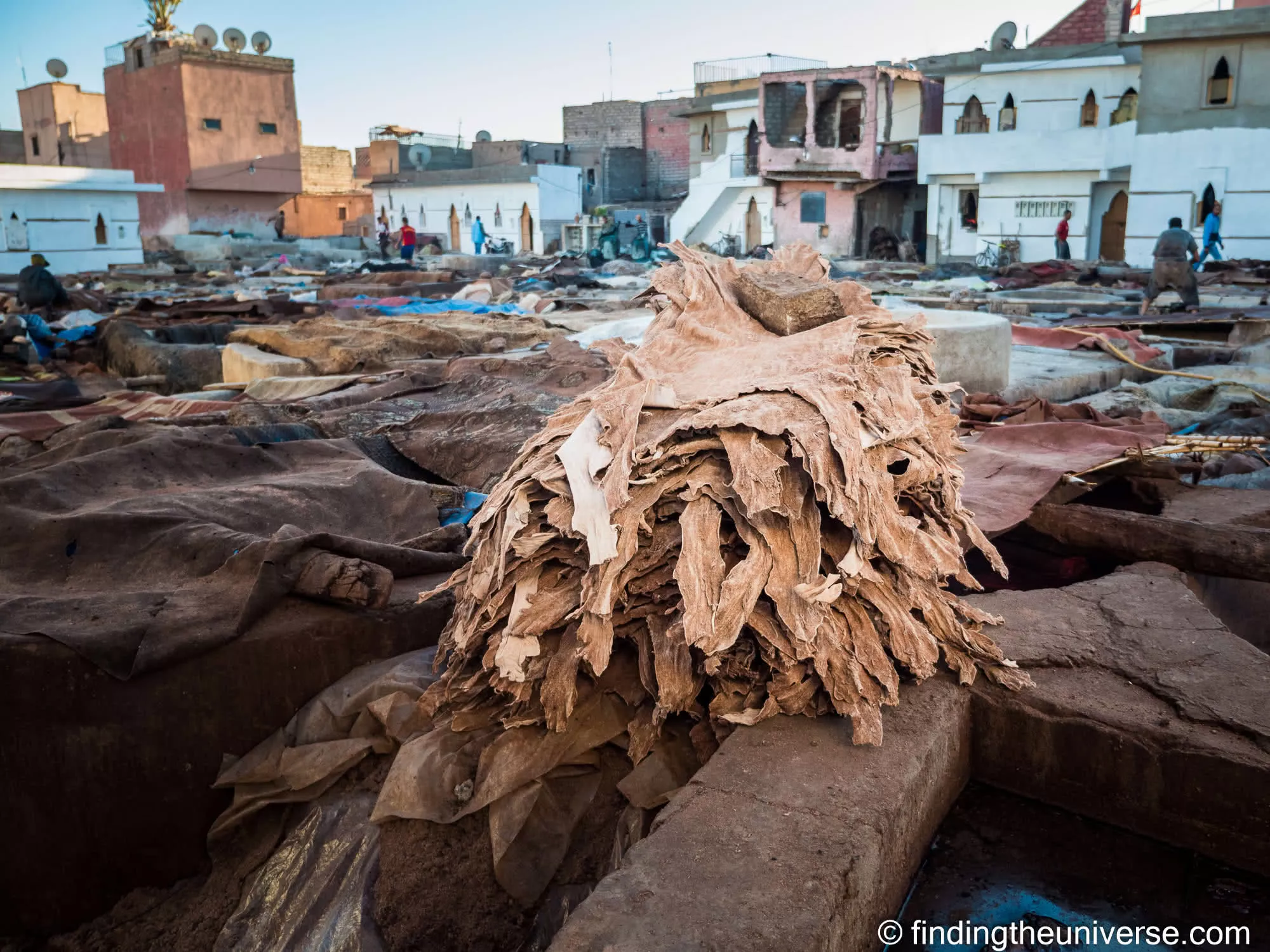 Animal hides drying in the open at a traditional tannery in Marrakesh, rooftops behind