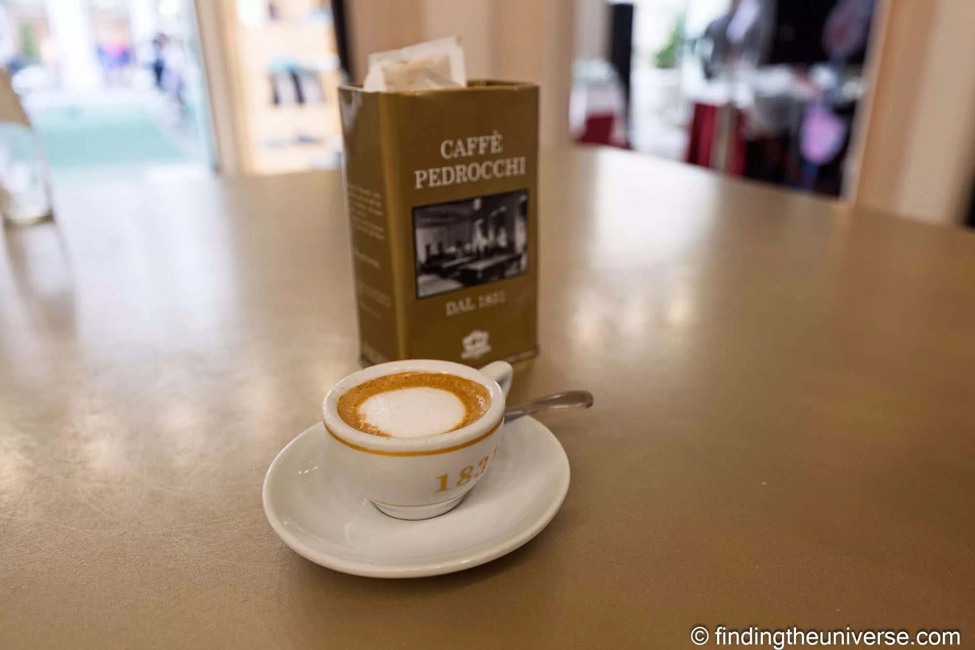 A signature Pedrocchi coffee in an 1831 cup beside a Caffè Pedrocchi tin in Padua