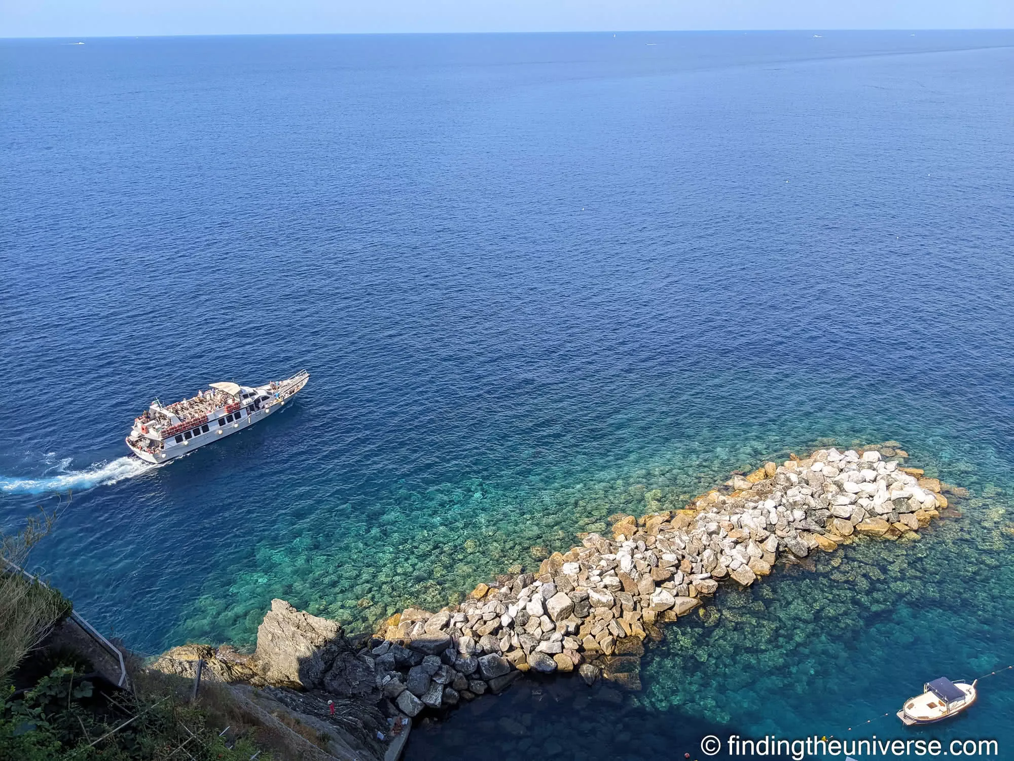 A coastal tour boat passing the Cinque Terre shoreline