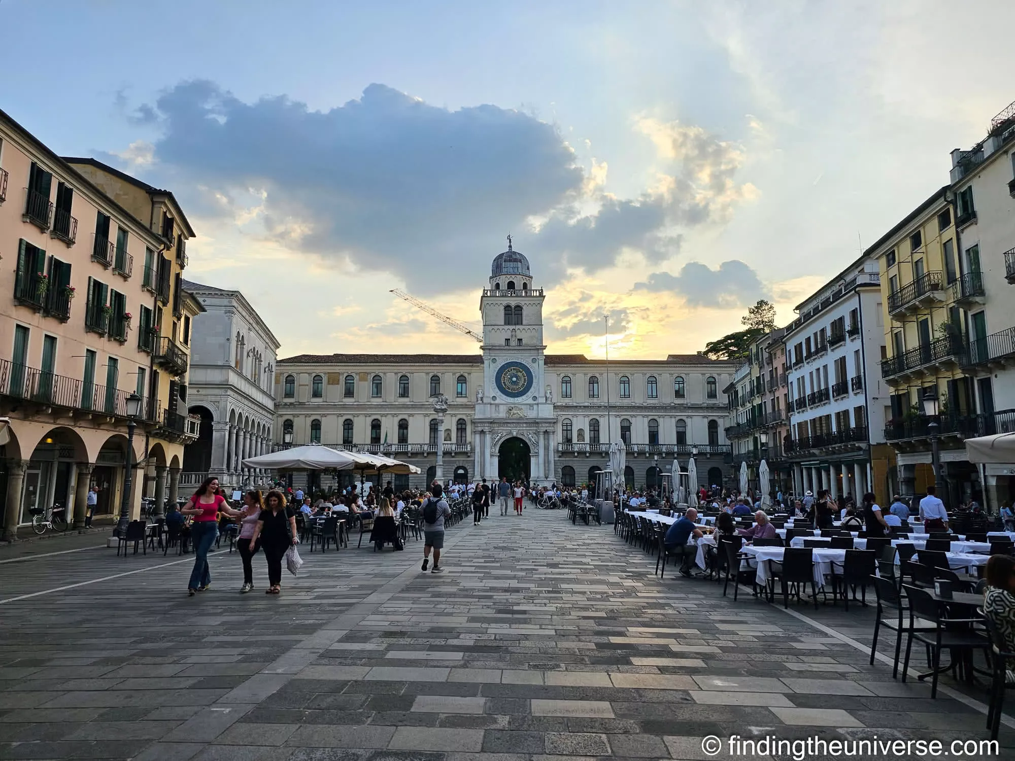 Restaurant tables set out under the arcades on Piazza dei Signori in Padua in the evening