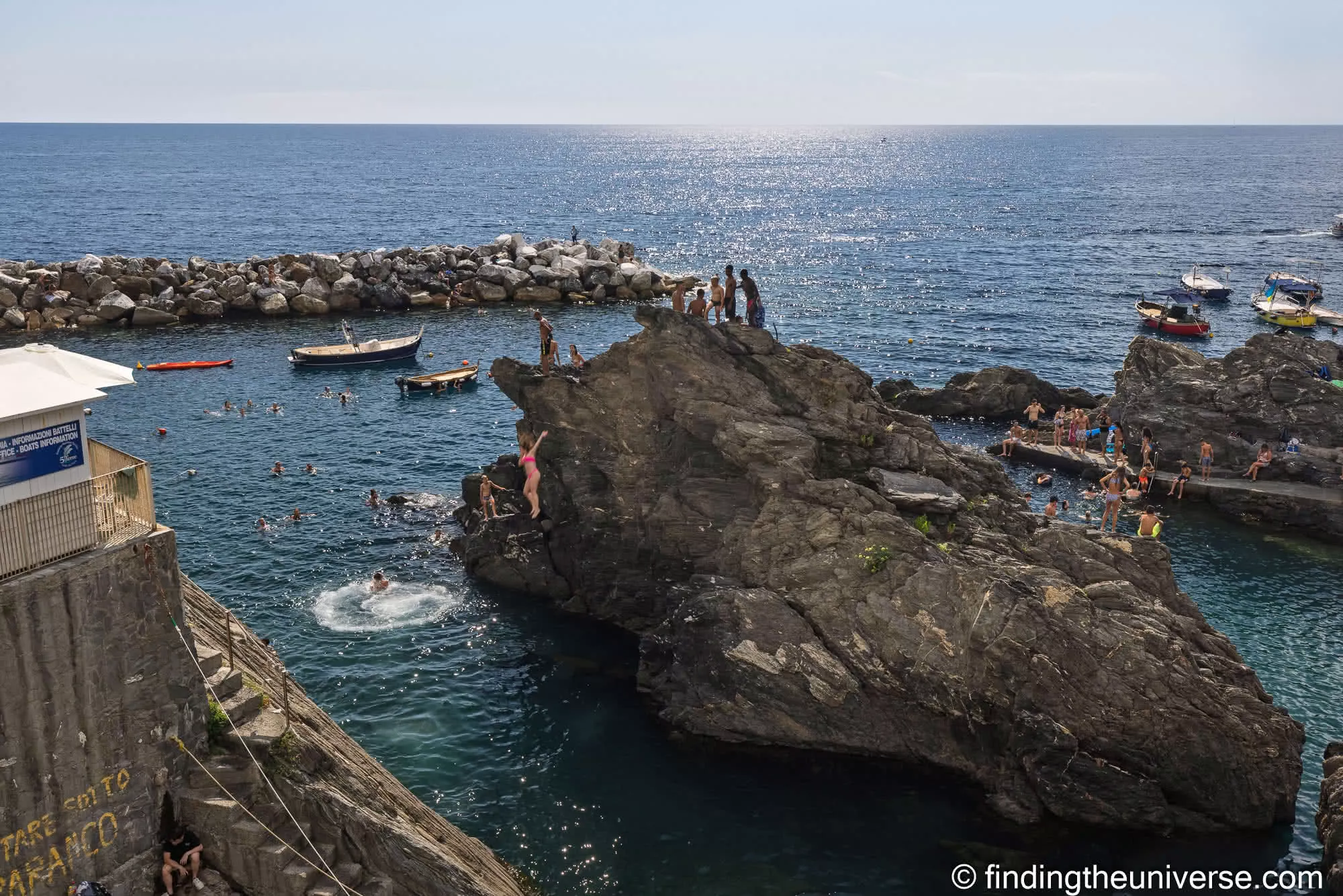 People swimming and jumping off the rocks in Manarola's harbour