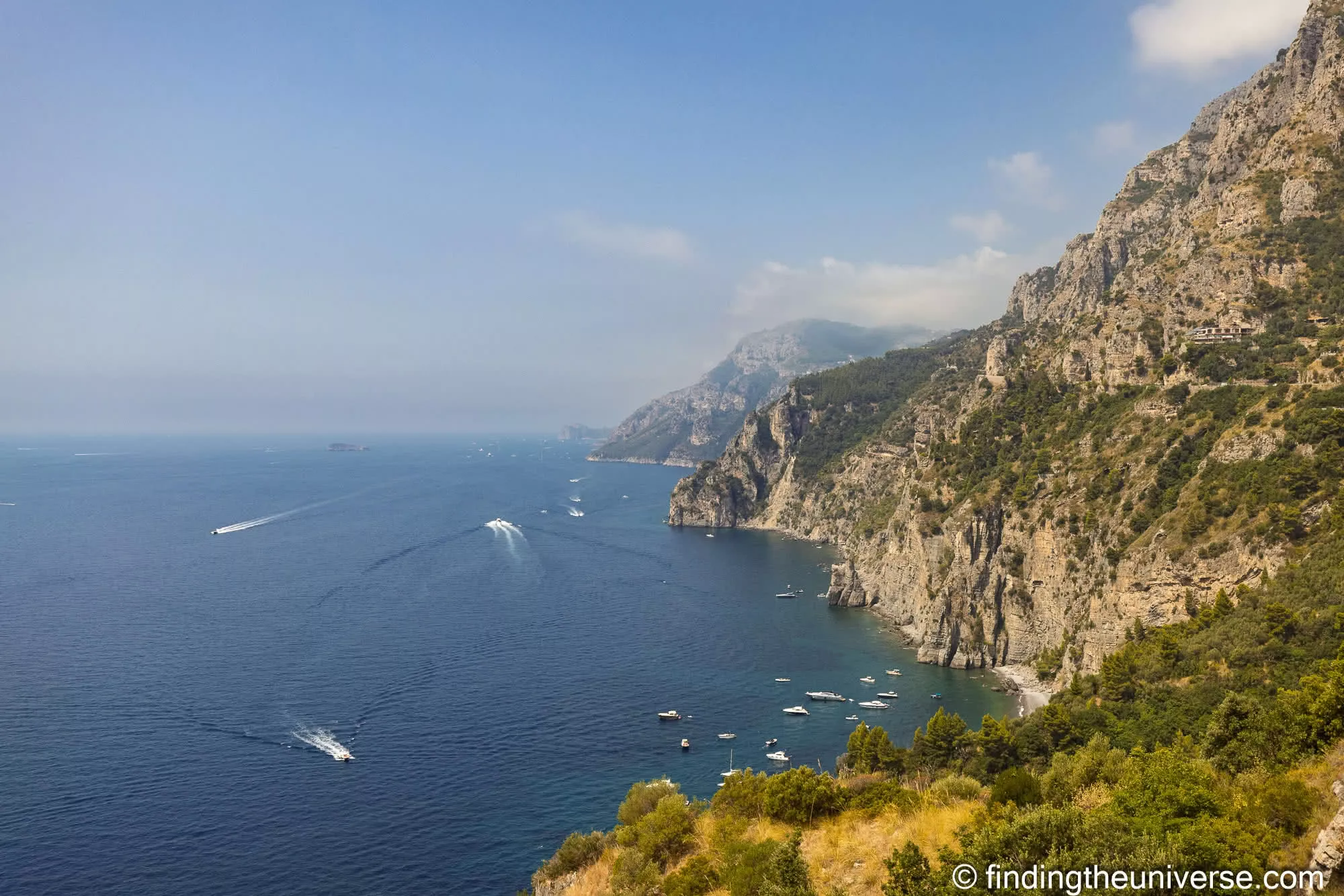 Cliffs of the Amalfi Coast dropping straight into the sea, with boats offshore
