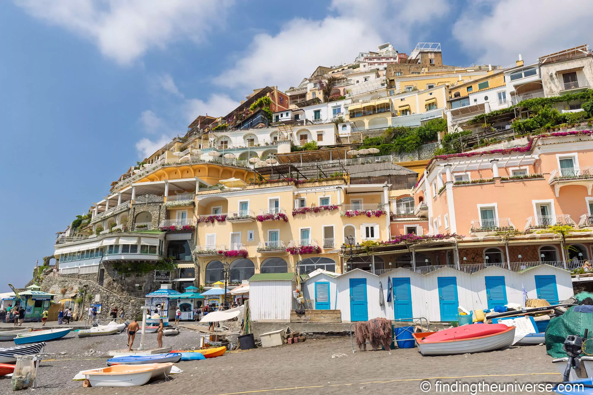 The pastel houses of Positano rising above the beach and its striped bathing huts