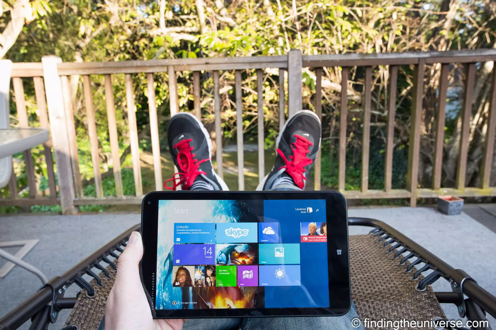 Small HP tablet held in one hand on a sunny deck