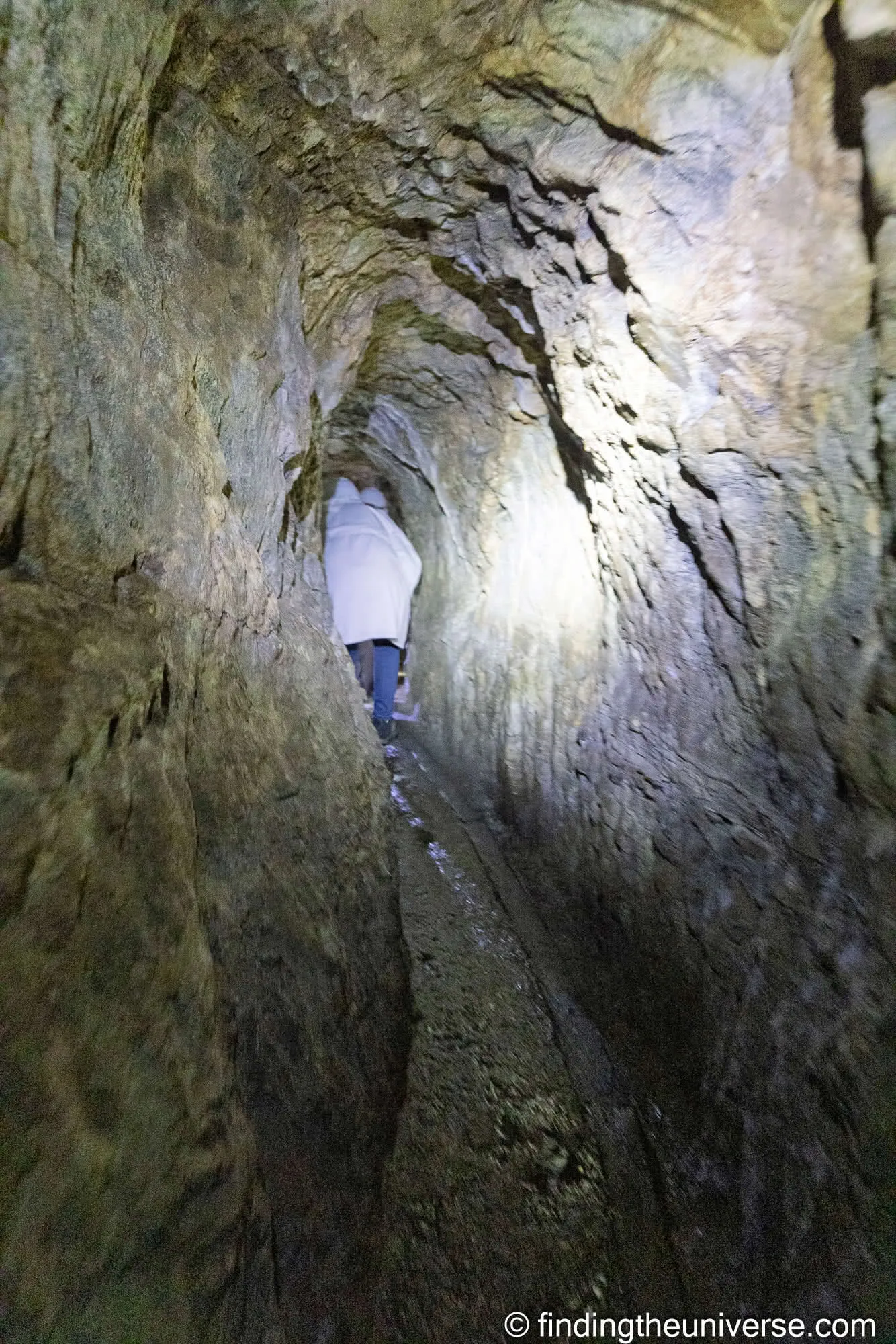 Visitor in a white coat squeezing through the silver mine, Kutná Hora