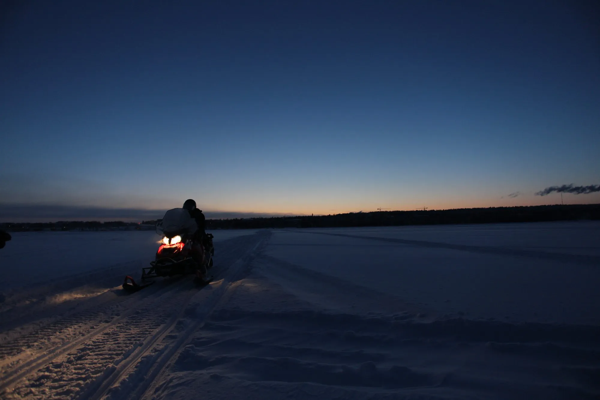 Snowmobile on a frozen lake at blue hour in Finnish Lapland